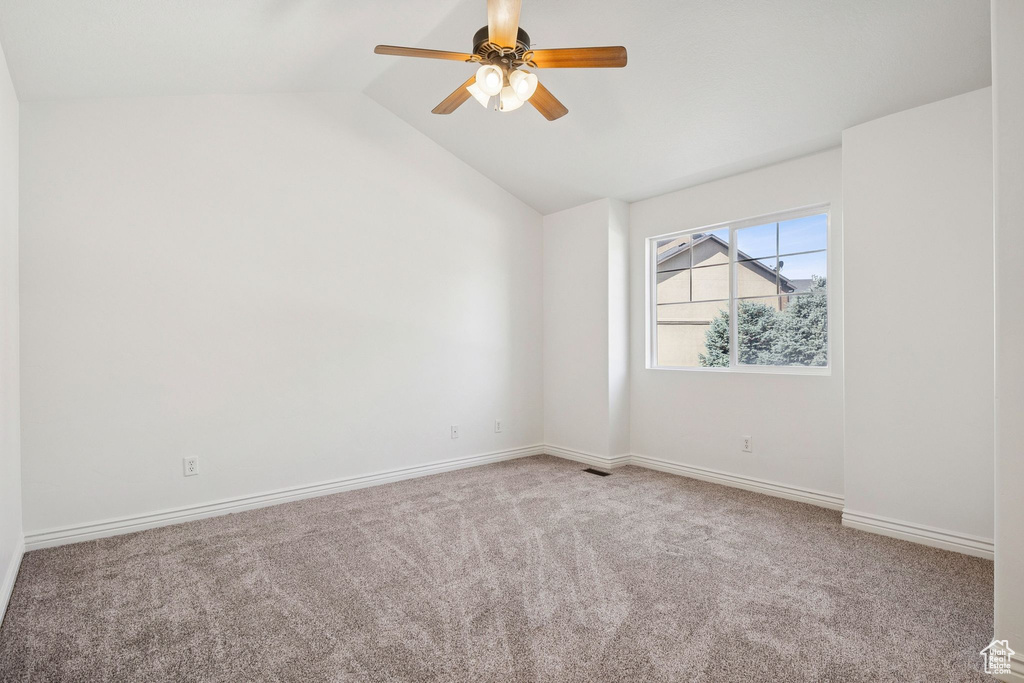 Carpeted spare room featuring lofted ceiling and a ceiling fan
