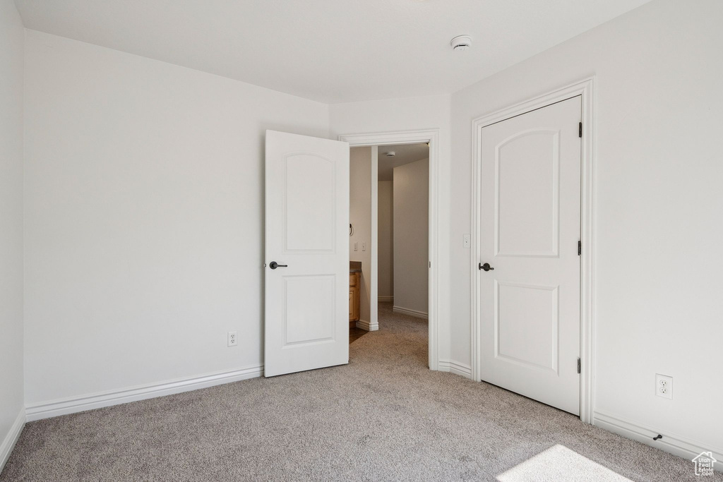 Unfurnished bedroom featuring light carpet and baseboards