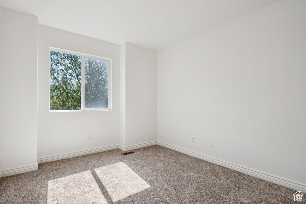 Carpeted spare room featuring baseboards