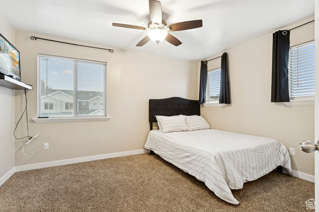 Carpeted bedroom with baseboards and a ceiling fan