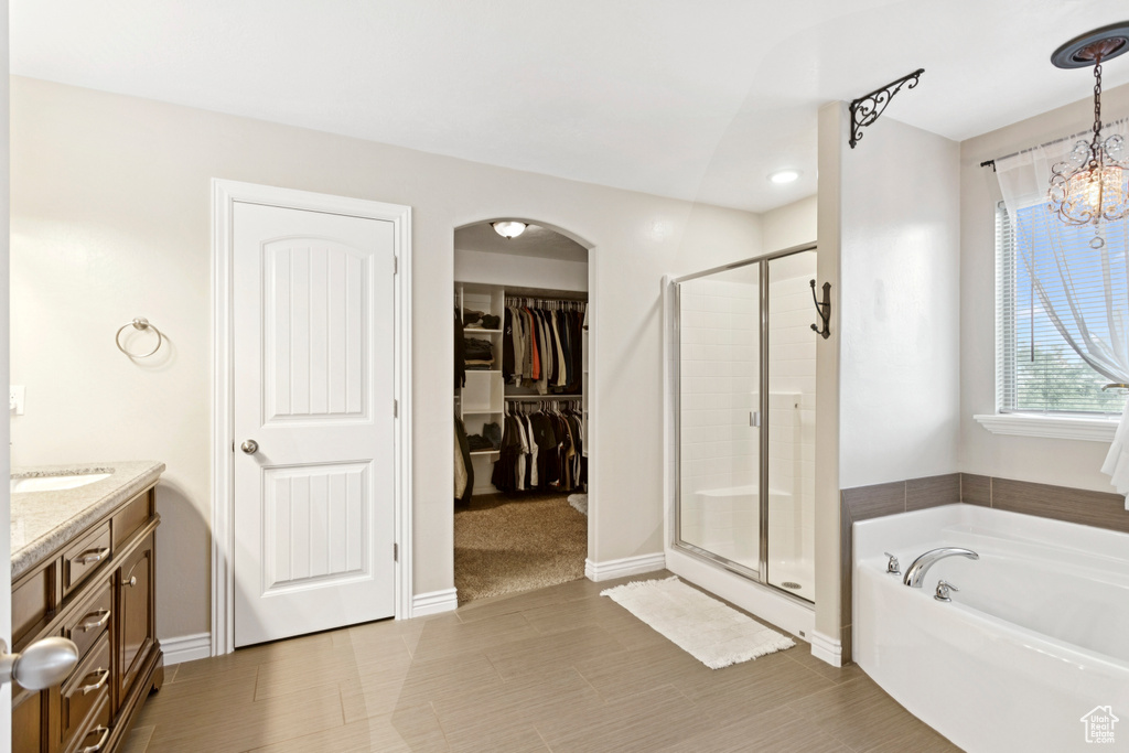 Full bathroom with a stall shower, a garden tub, vanity, a spacious closet, and a chandelier
