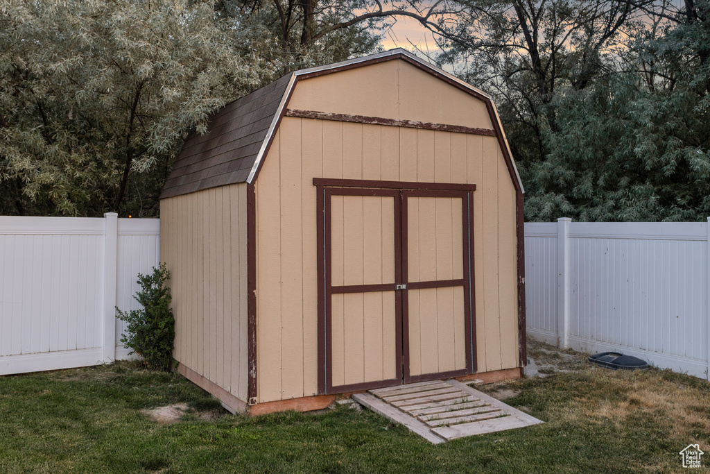 Outdoor structure at dusk with a fenced backyard and a shed