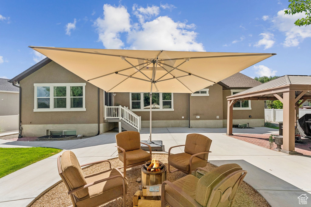 Rear view of house with an outdoor fire pit, a gazebo, stucco siding, and a patio area