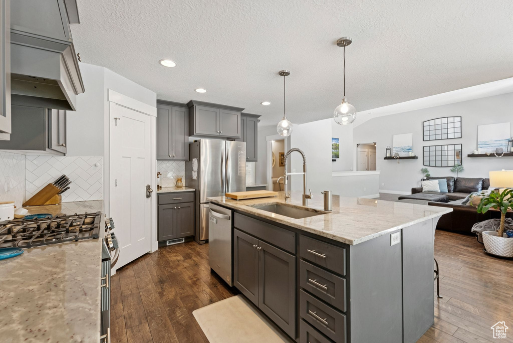Kitchen featuring stainless steel appliances, gray cabinetry, tasteful backsplash, dark wood-type flooring, and a textured ceiling