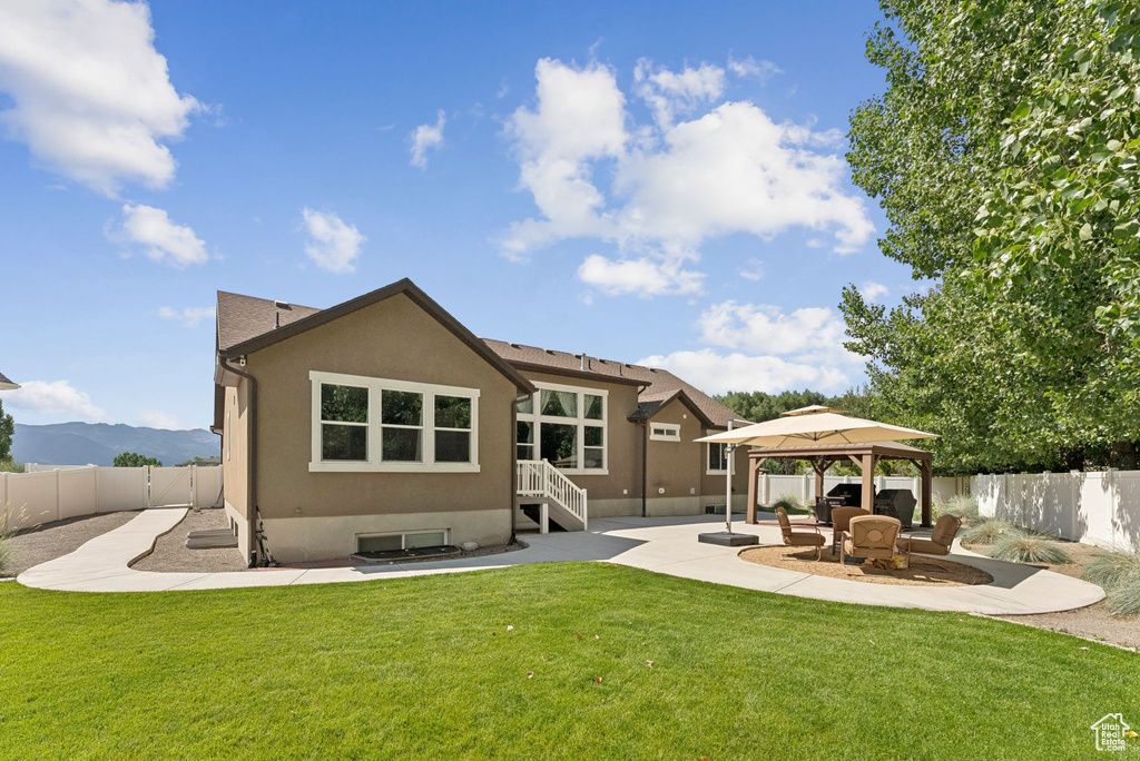 Back of house with a gazebo, a fenced backyard, stucco siding, and a patio area