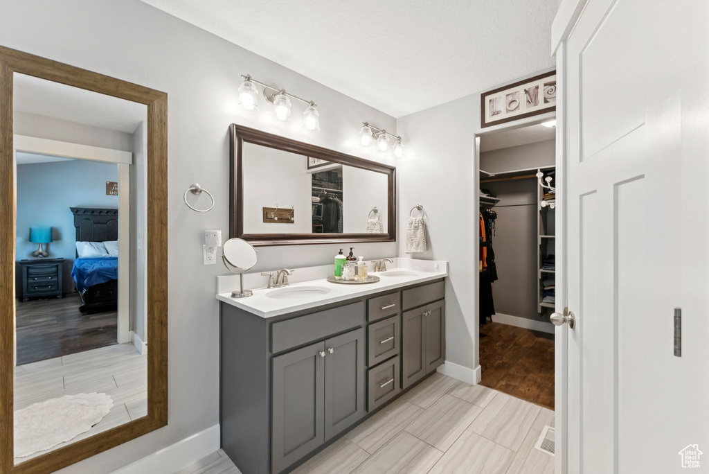Ensuite bathroom featuring double vanity and a walk in closet