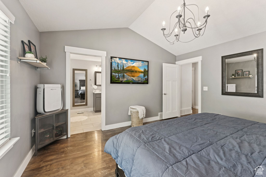 Bedroom featuring vaulted ceiling, dark wood-style flooring, a chandelier, and ensuite bathroom