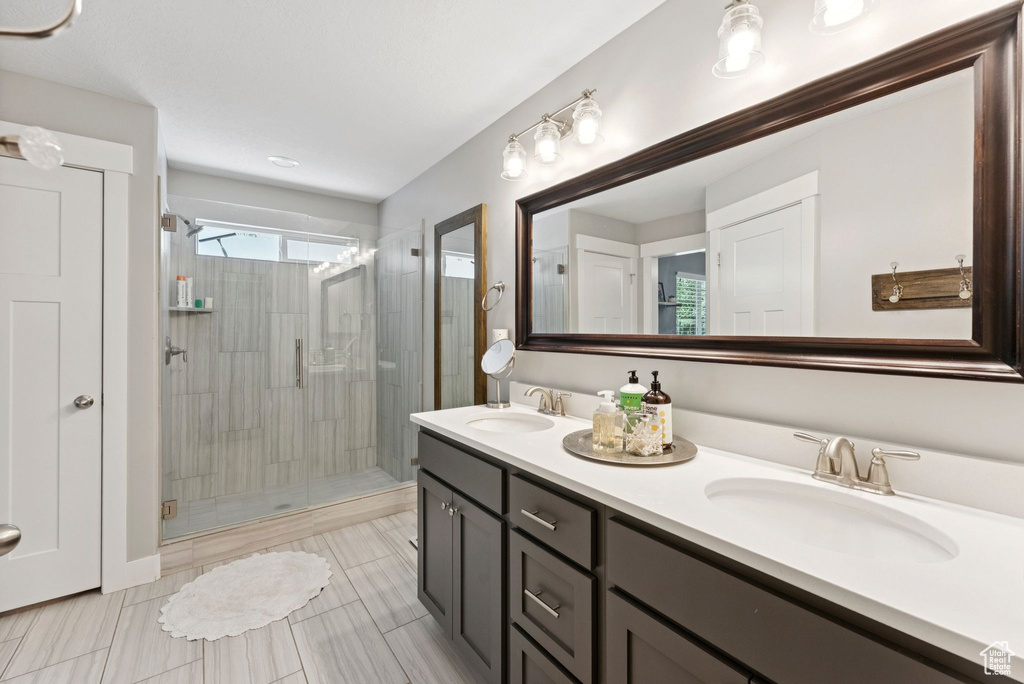 Bathroom with a shower stall, double vanity, and tile patterned flooring