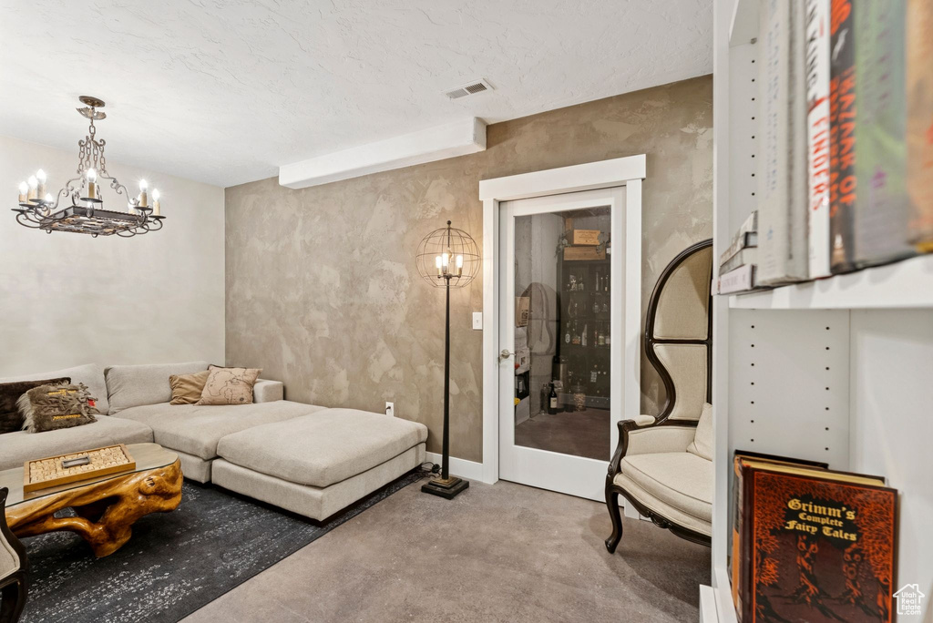 Living room with carpet floors, a chandelier, and a textured ceiling