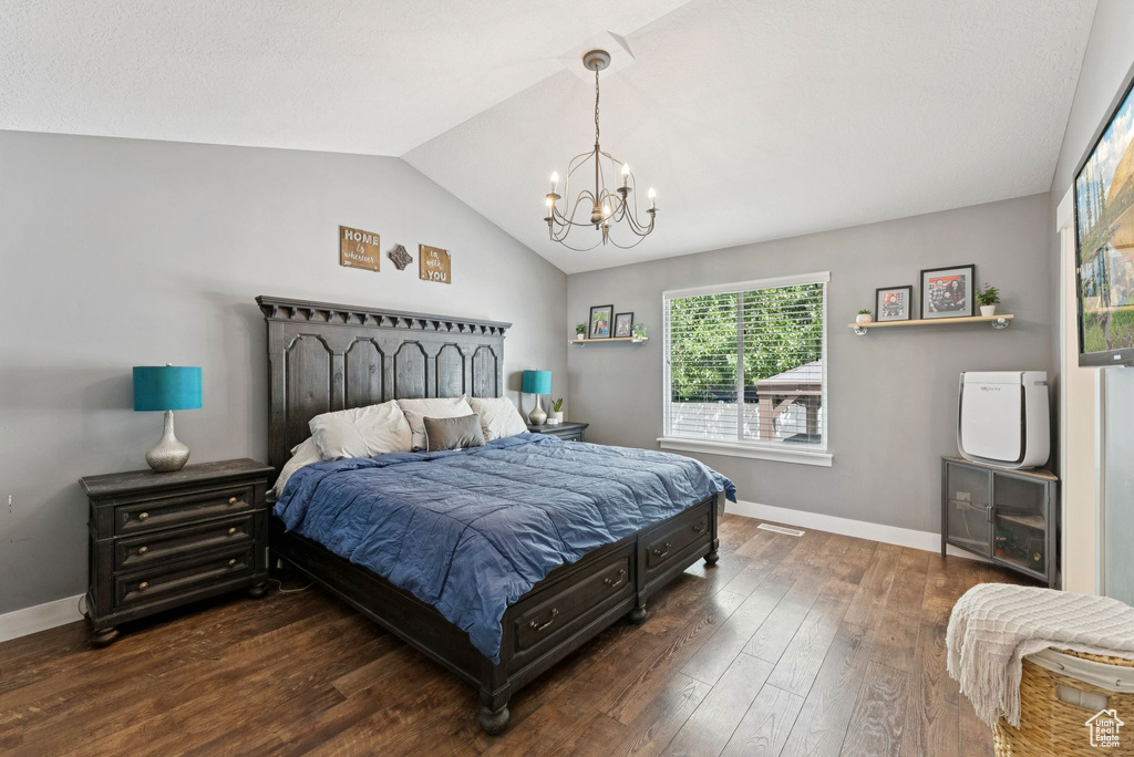 Bedroom featuring a chandelier, vaulted ceiling, and dark wood-type flooring