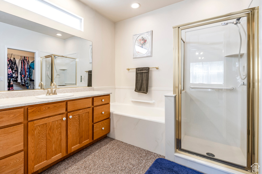 Bathroom with a stall shower, vanity, a bath, and a walk in closet