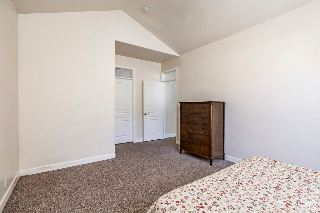 Carpeted bedroom with lofted ceiling and baseboards