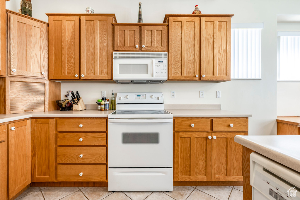 Kitchen with white appliances, light tile patterned flooring, and light countertops