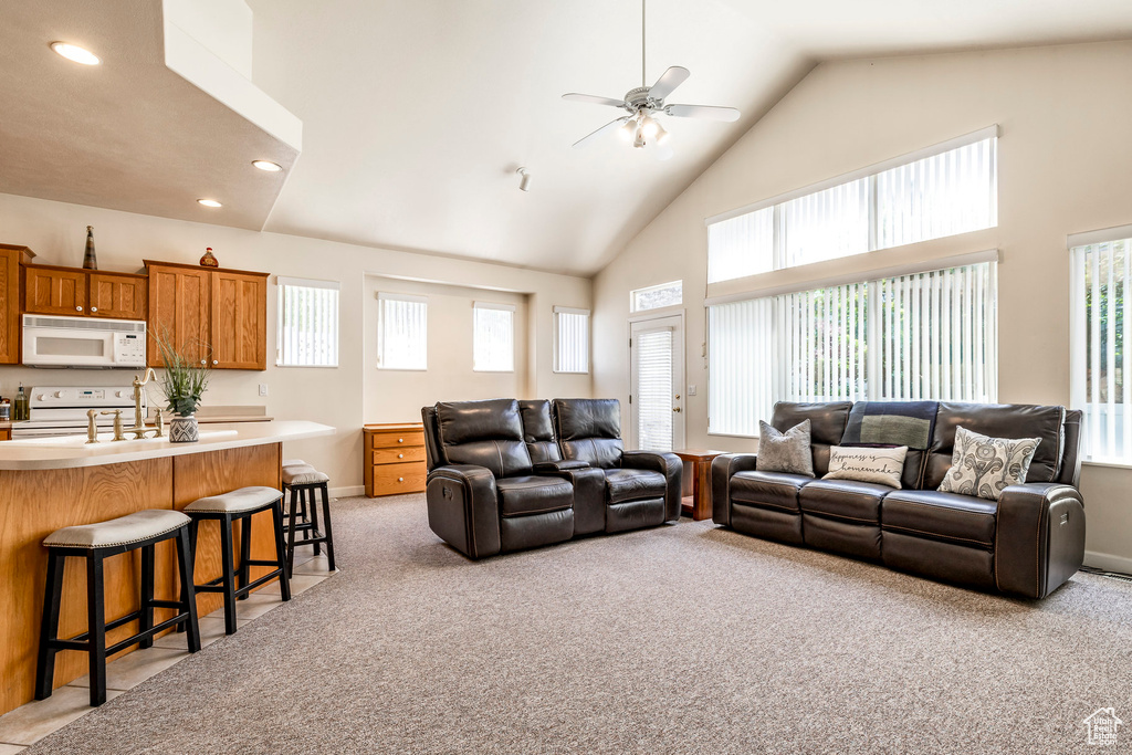 Living room with high vaulted ceiling, ceiling fan, light carpet, plenty of natural light, and recessed lighting