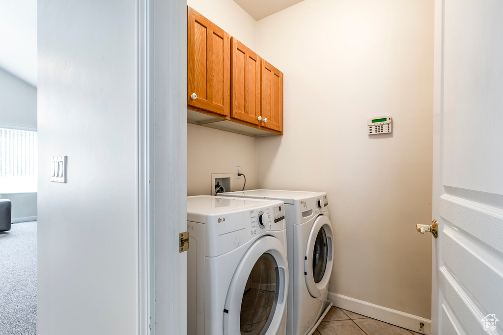 Laundry room featuring separate washer and dryer, cabinet space, and light tile patterned floors