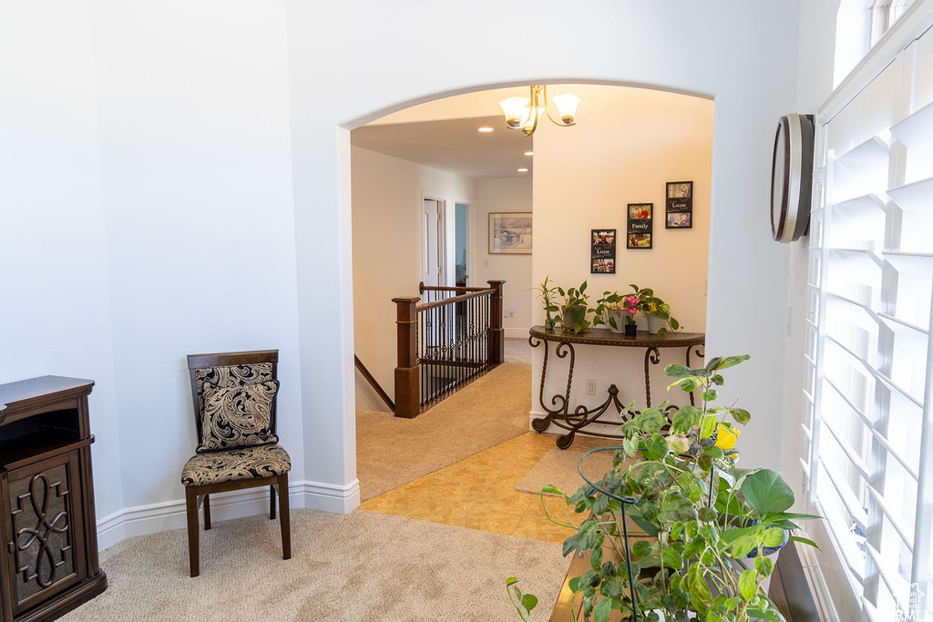 Living area featuring carpet, arched walkways, an upstairs landing, a chandelier, and recessed lighting