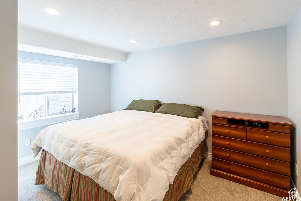 Bedroom with light colored carpet and recessed lighting
