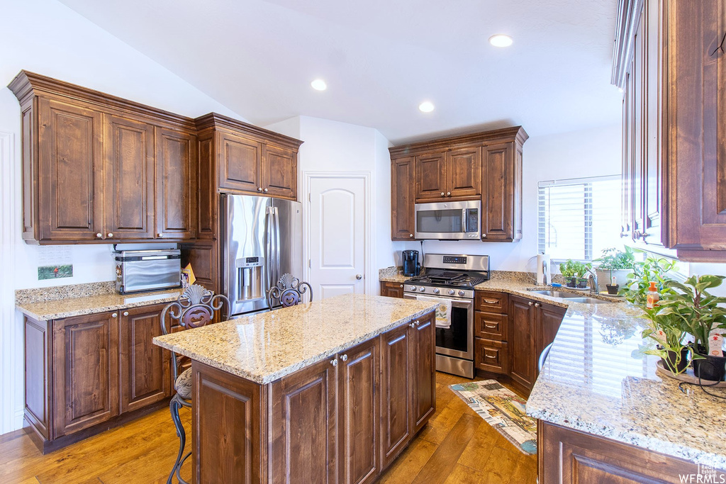 Kitchen featuring appliances with stainless steel finishes, a center island, light stone countertops, and recessed lighting