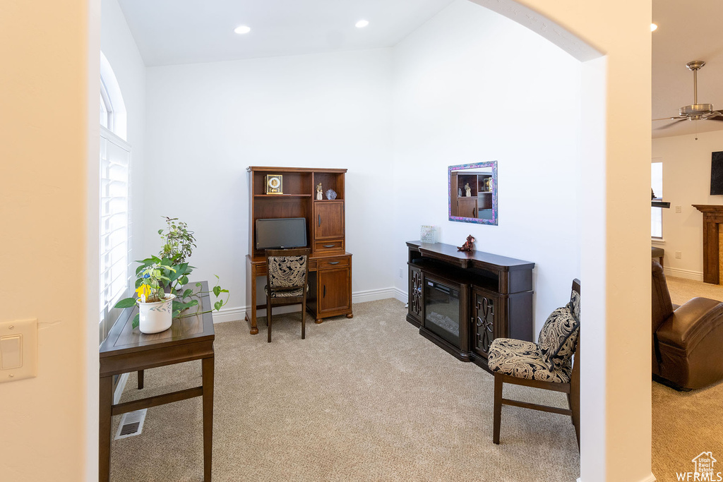 Office area with a glass covered fireplace, light colored carpet, arched walkways, recessed lighting, and ceiling fan