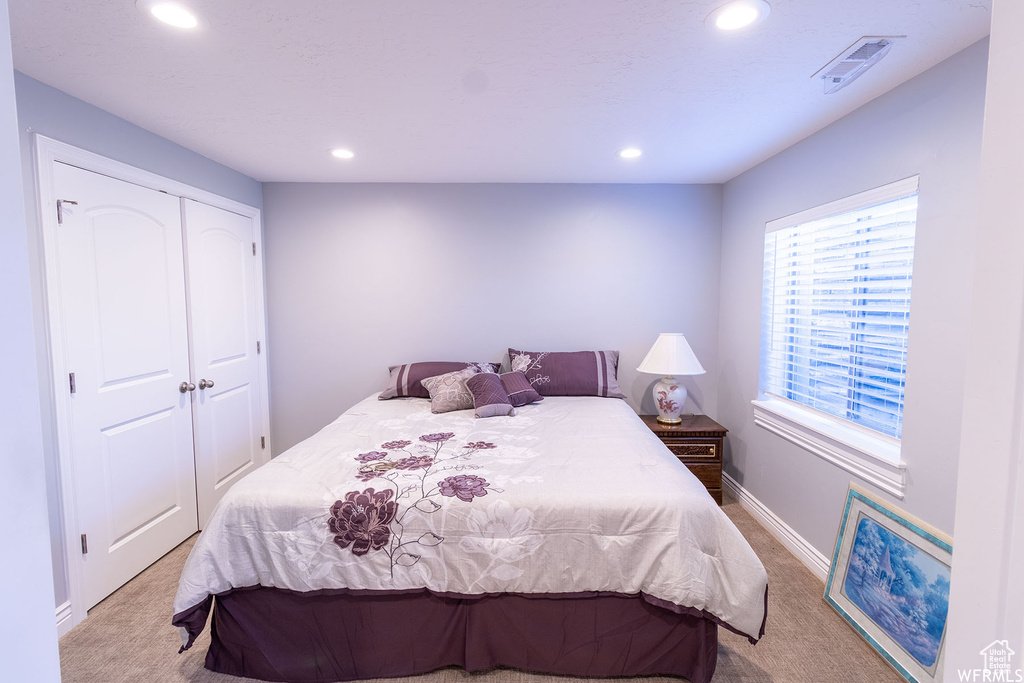 Bedroom with light carpet, recessed lighting, and a closet