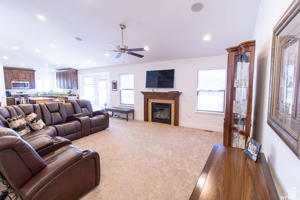 Living area featuring recessed lighting, light colored carpet, a glass covered fireplace, healthy amount of natural light, and ceiling fan