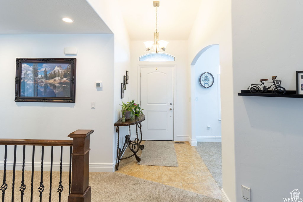 Foyer with arched walkways, a chandelier, tile patterned floors, carpet, and recessed lighting
