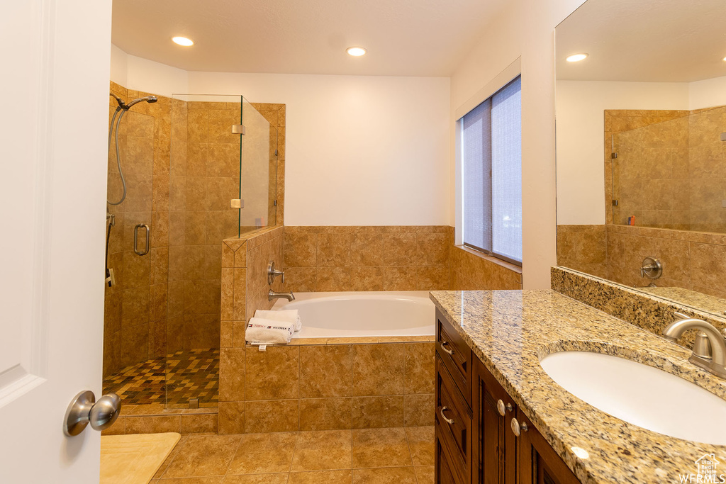 Bathroom featuring a stall shower, vanity, a garden tub, and recessed lighting