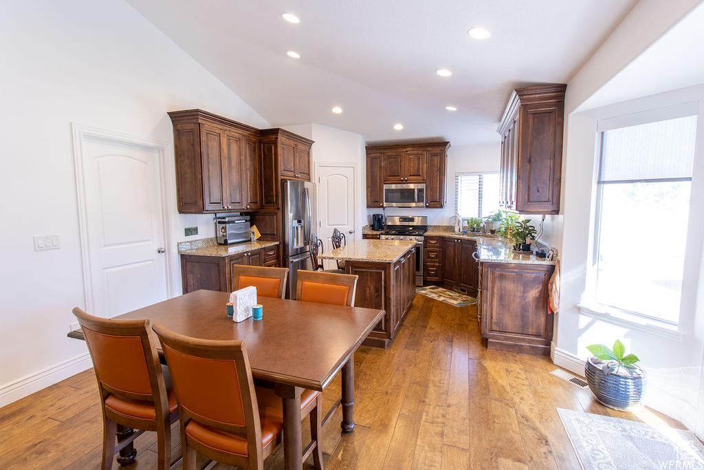 Kitchen featuring stainless steel appliances, a kitchen island, recessed lighting, light wood-style floors, and vaulted ceiling