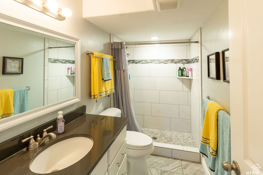 Full bath with a tile shower, vanity, and marble look tiles