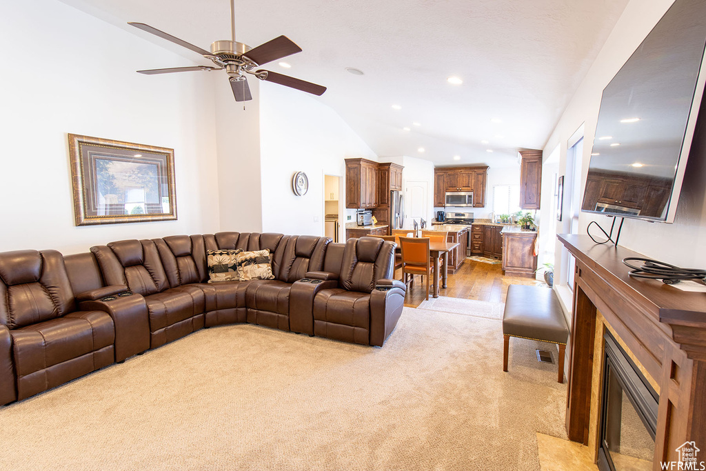 Living area featuring lofted ceiling, light colored carpet, ceiling fan, recessed lighting, and light wood-style floors