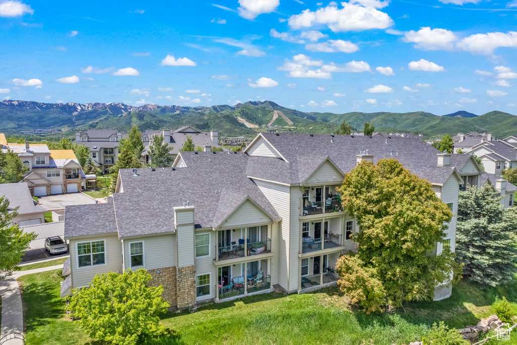 Rear view of property featuring a mountain view, a balcony, a residential view, and roof with shingles