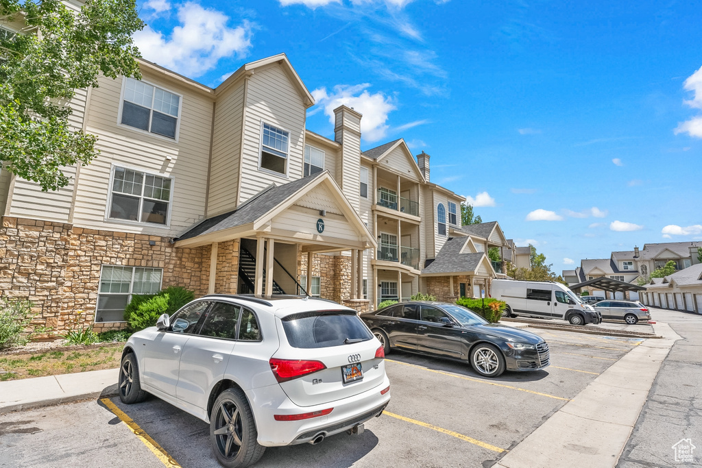 Multi unit property with uncovered parking, stone siding, and a residential view