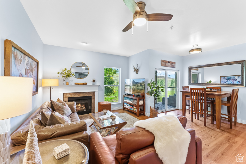 Living area with a fireplace, light wood finished floors, and a ceiling fan