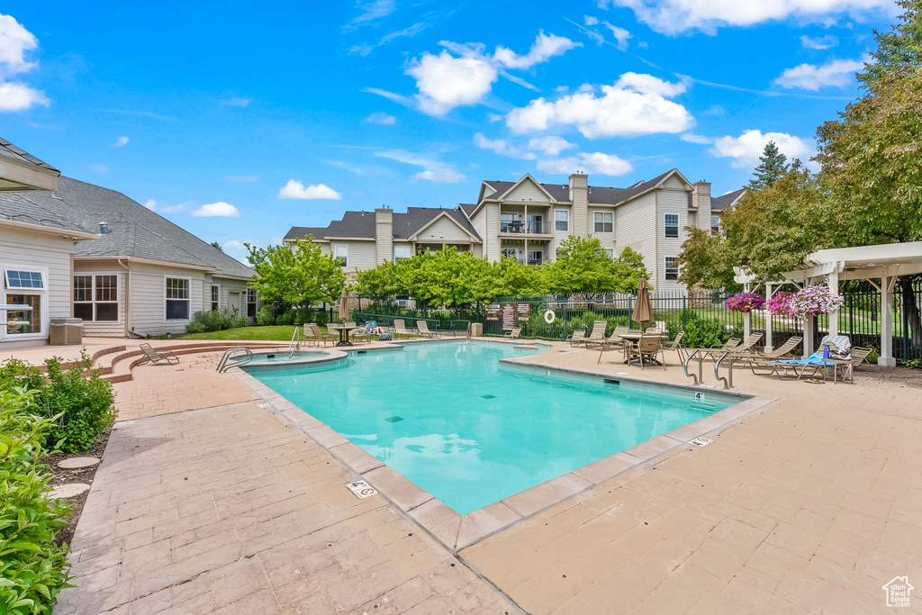 Community pool with a patio area, a pergola, and a residential view