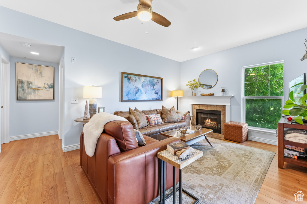 Living room with ceiling fan, light wood-type flooring, and a fireplace