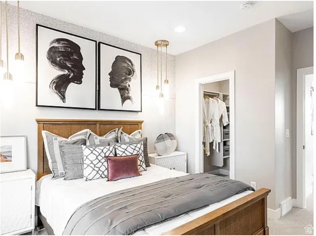 Bedroom featuring a walk in closet, light carpet, and a closet