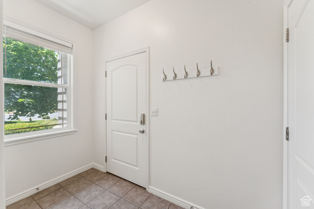 Doorway to outside featuring light tile patterned floors and baseboards