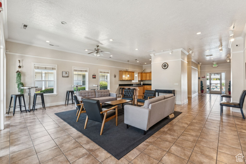 Living area featuring light tile patterned flooring, a textured ceiling, crown molding, a ceiling fan, and recessed lighting