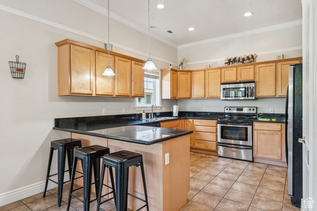 Kitchen with stainless steel appliances, a peninsula, light tile patterned floors, crown molding, and pendant lighting