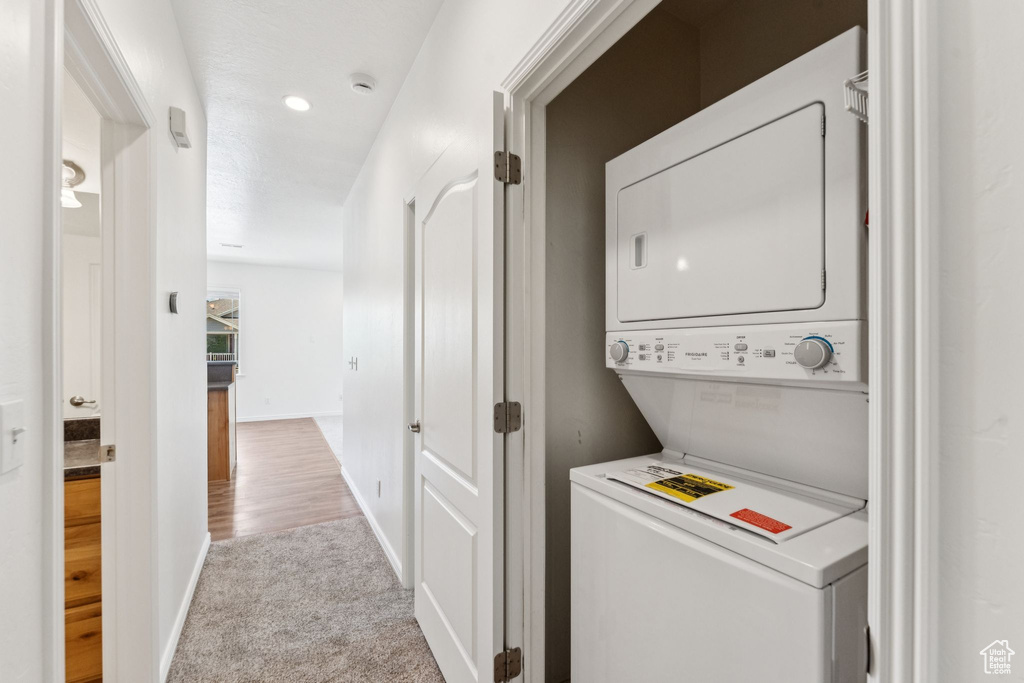 Laundry room with stacked washer / drying machine and carpet