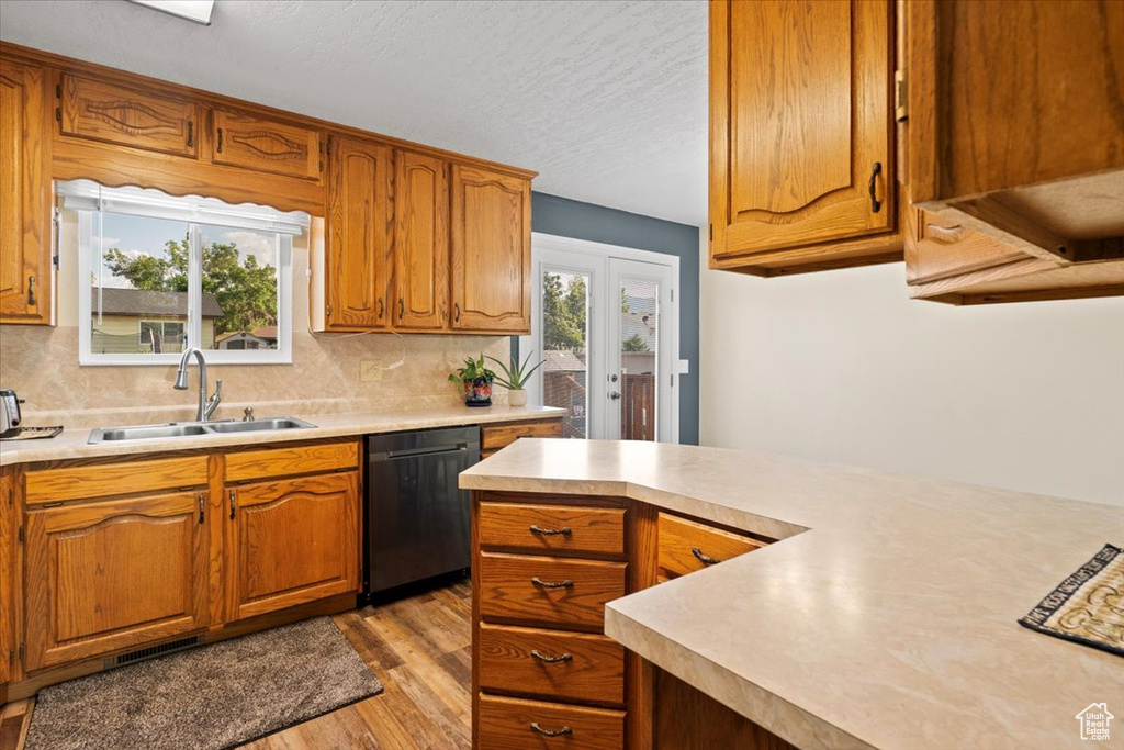 Kitchen featuring dishwashing machine, light countertops, light wood-style flooring, backsplash, and a textured ceiling