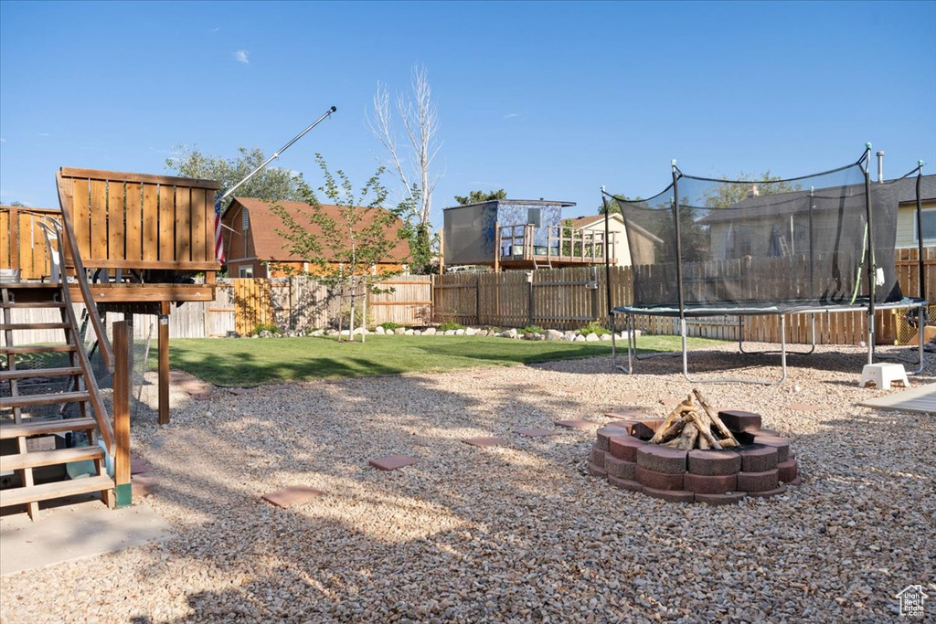 View of yard featuring a trampoline and a fire pit