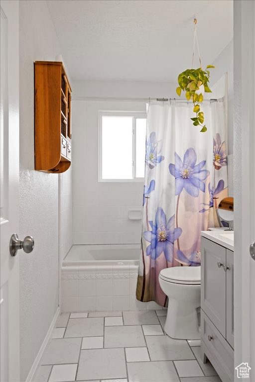 Full bath with vanity, marble look tile flooring, and tiled shower / bath combo