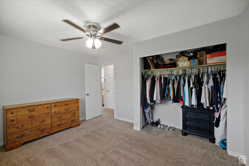 Carpeted bedroom with a closet, a textured ceiling, and a ceiling fan