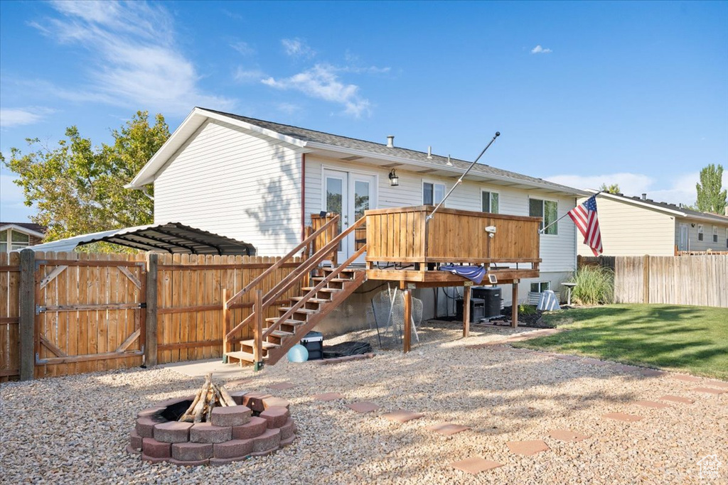 Back of property with a fire pit, stairway, french doors, and a wooden deck