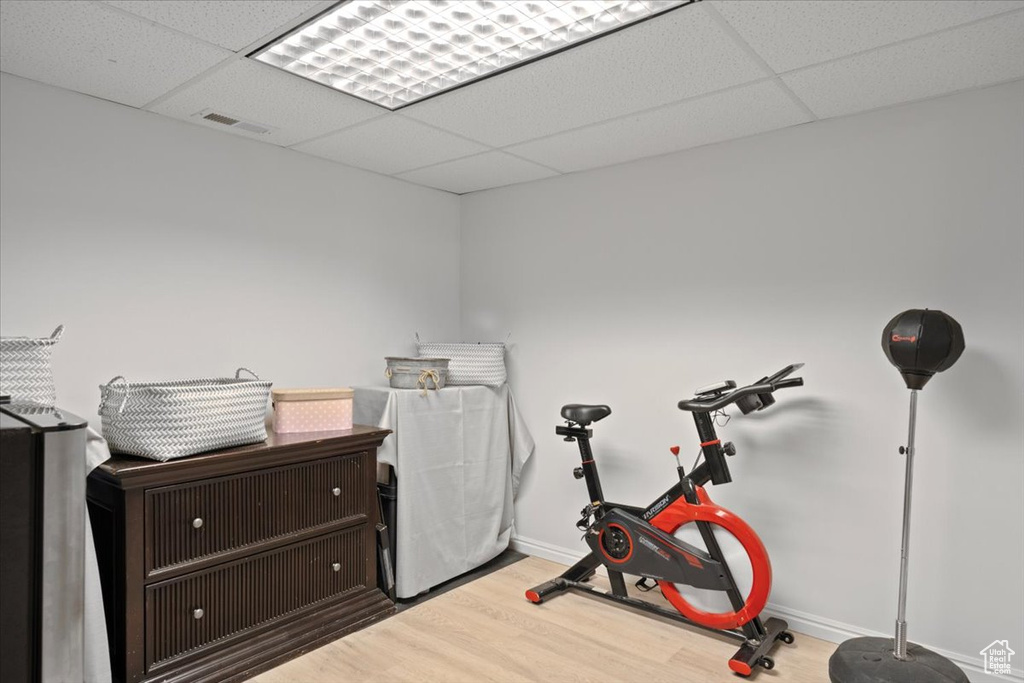 Workout area featuring wood finished floors and a drop ceiling