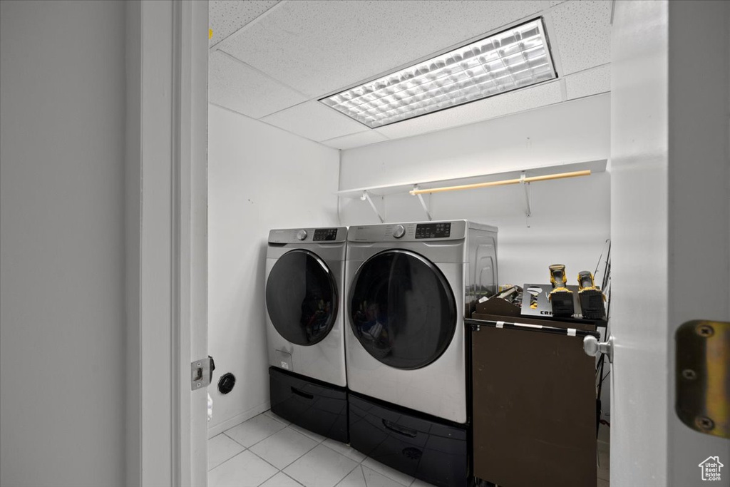 Laundry room with washer and clothes dryer and light tile patterned flooring