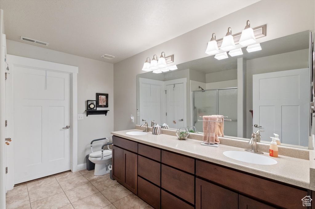 Full bath with double vanity, a stall shower, and tile patterned floors