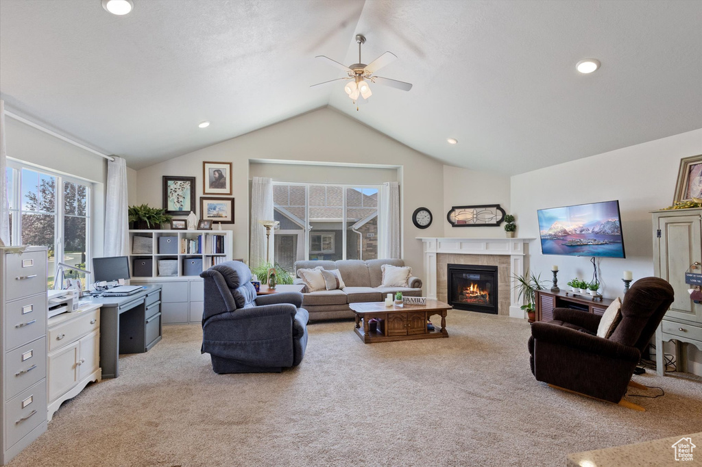 Living room with light colored carpet, vaulted ceiling, a ceiling fan, a tiled fireplace, and recessed lighting