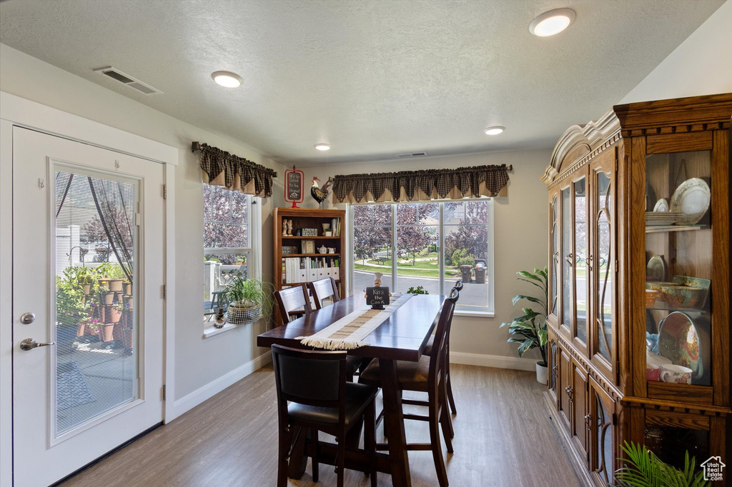 Dining area featuring a textured ceiling, wood finished floors, and recessed lighting